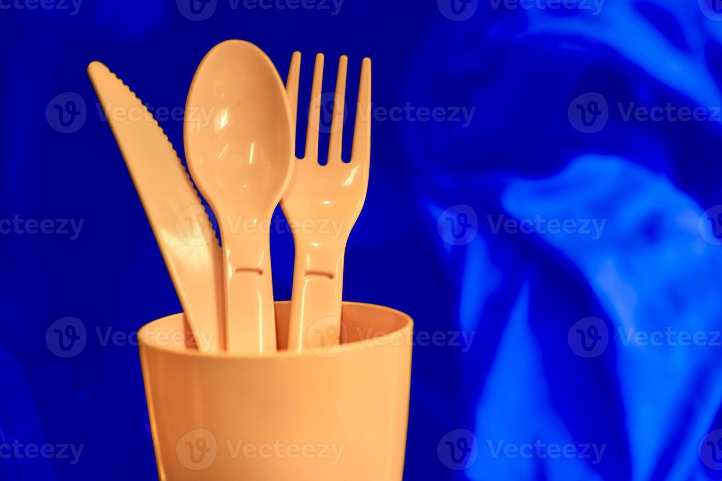 Camping.Pink plastic dinnerware set on blue.Cup,fork,knife,spoon photo