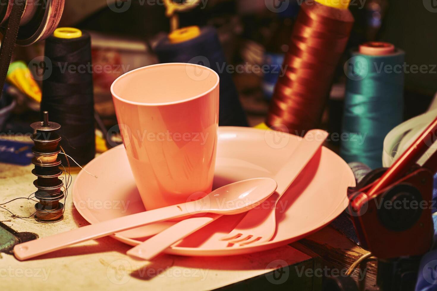 Orange plastic dinnerware set in tailor sewing workshop.Cup,fork,knife,spoon photo