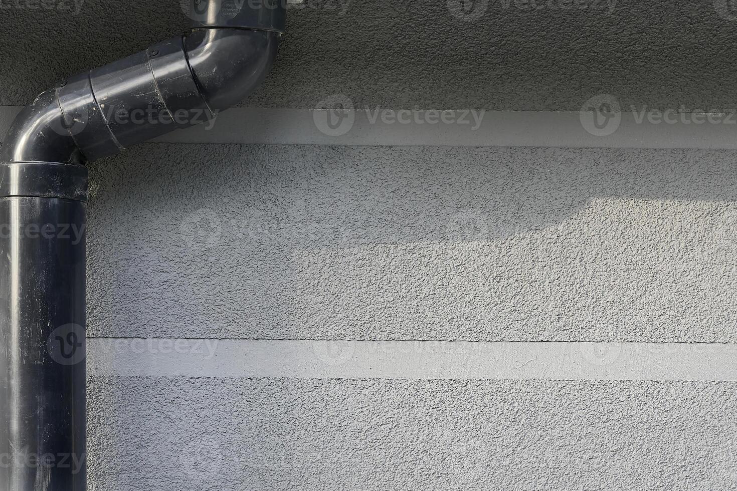 Rain runoff.New plastic drain pipe on a gray plastered wall photo