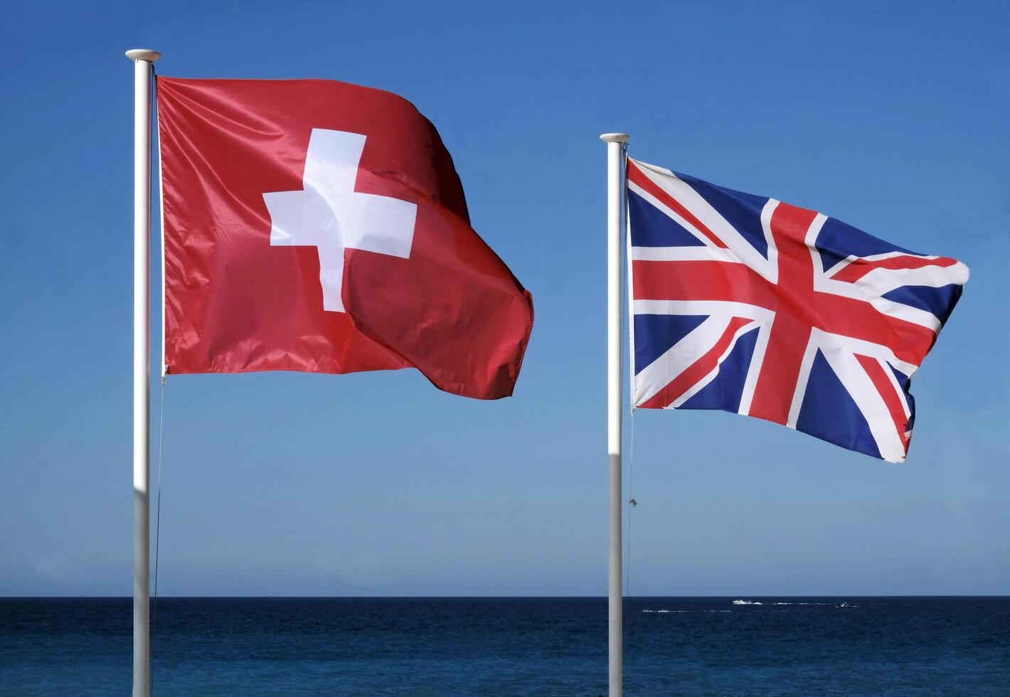 The national flags of Switzerland and the United Kingdom next to the sea photo