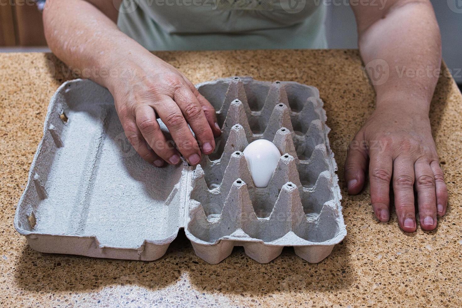 One last white egg in egg carton and hands. photo