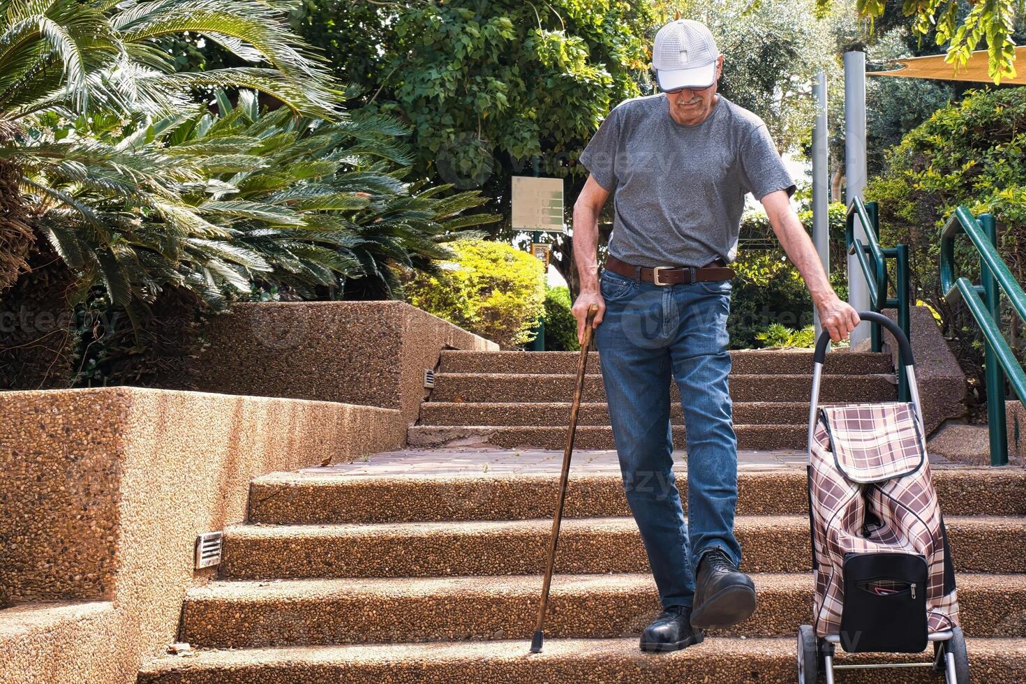 Elderly man walking down the stairs with a walking stick. photo