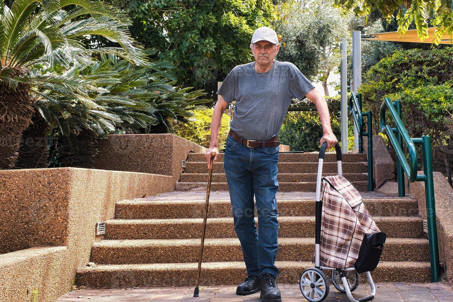 Elderly man walking down the stairs with a walking stick. photo
