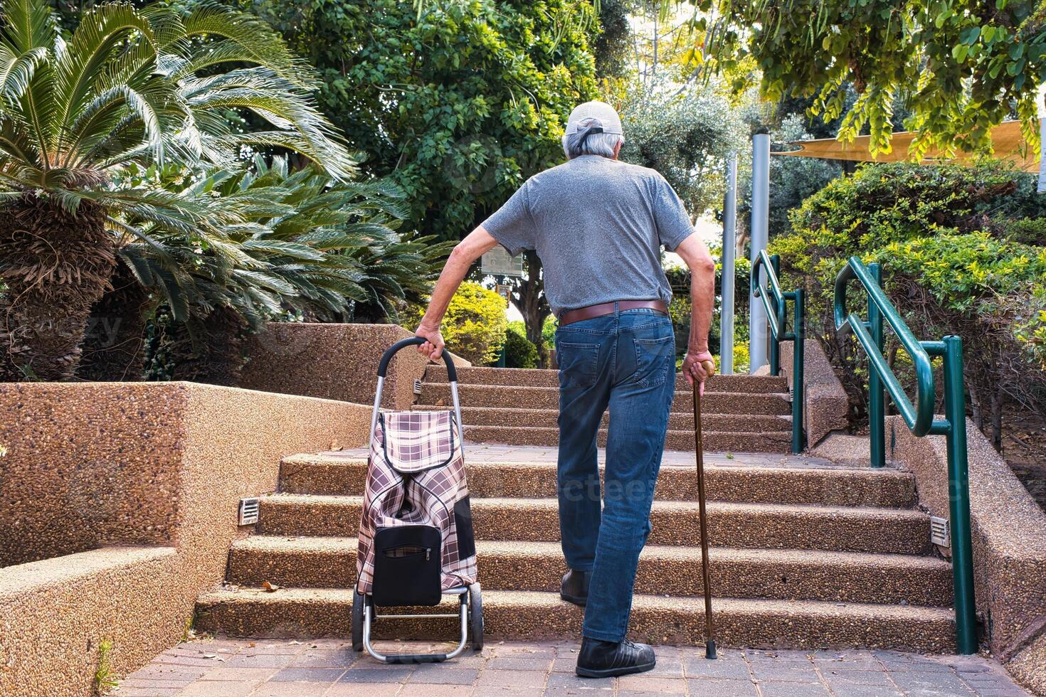 Elderly man walking up the stairs with a walking stick photo