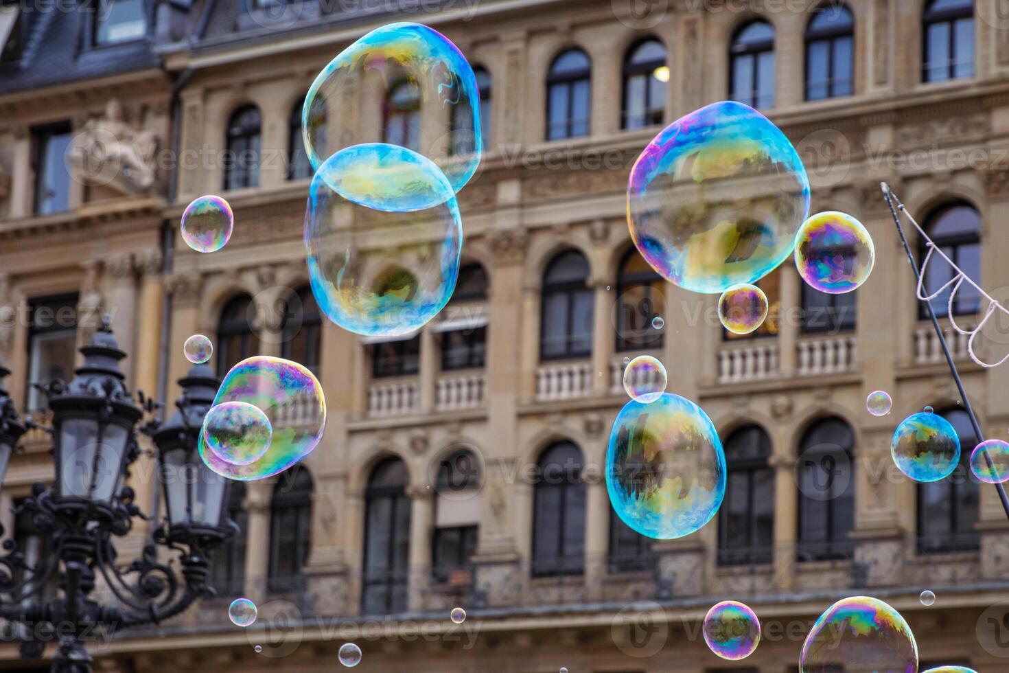 Many multicolored giant soap bubbles flying in the air on a windy day. Huge bubble are stretching on the wind into long smoothy changing form without popping. Close up. Copy space. Selective focus. photo