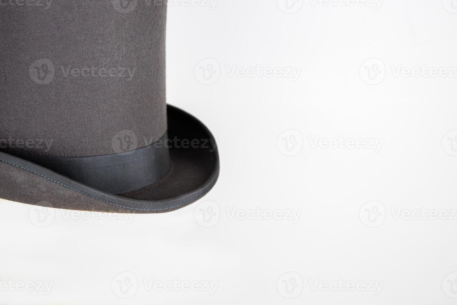 Magic hat. Topper. Elegant vintage gray beige wool felt top hat with black band on the wooden hat block. Grosgrain ribbon trim around rolled brim. Isolated on white background. Close-up. Copy space. photo