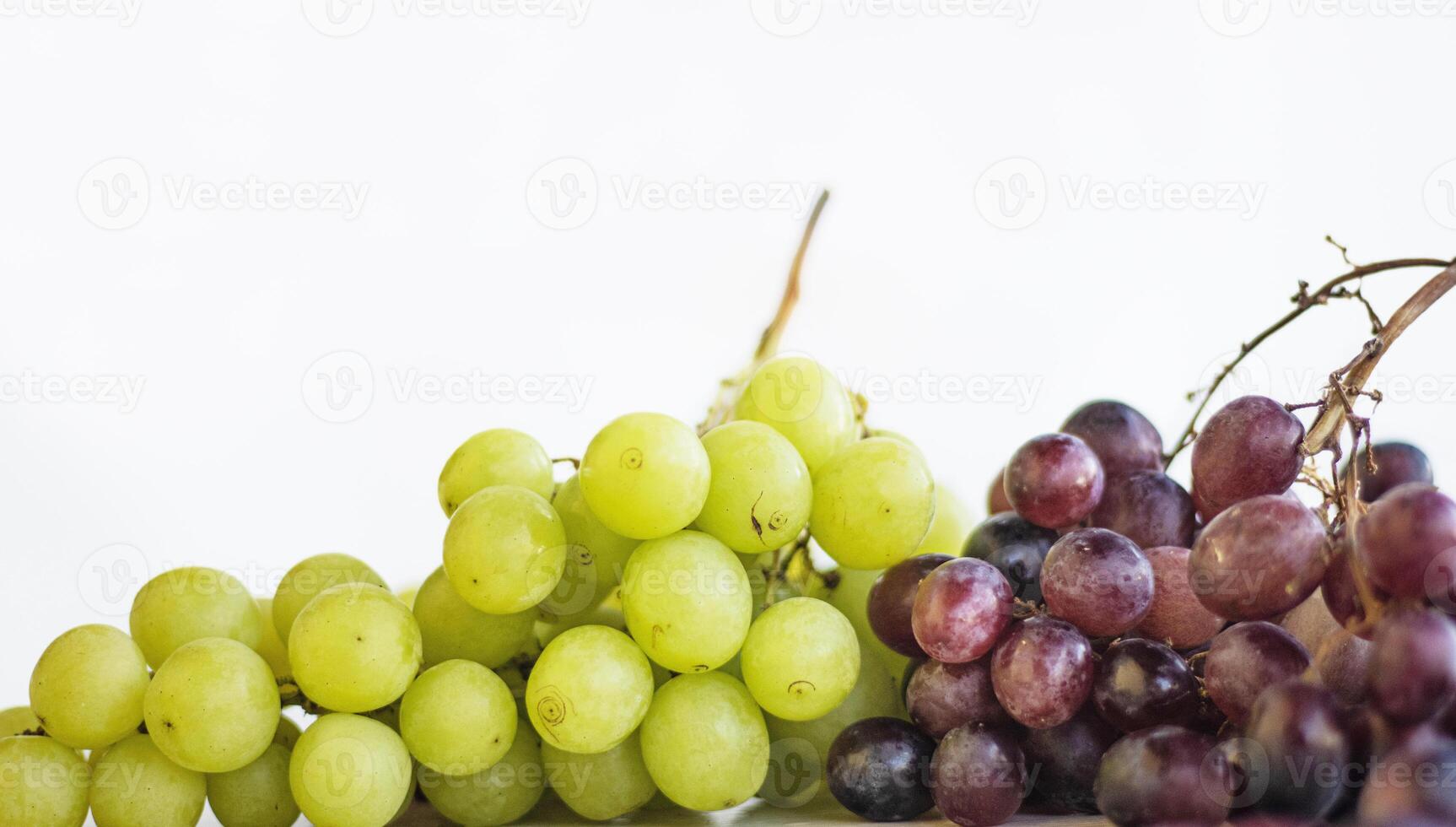 Close up of a bunch of white and red or purple grapes. Fresh bunches of green and blue grapes on the wooden table, isolated on white background. Healthy fruits concept. Copy space. Selective focus. photo