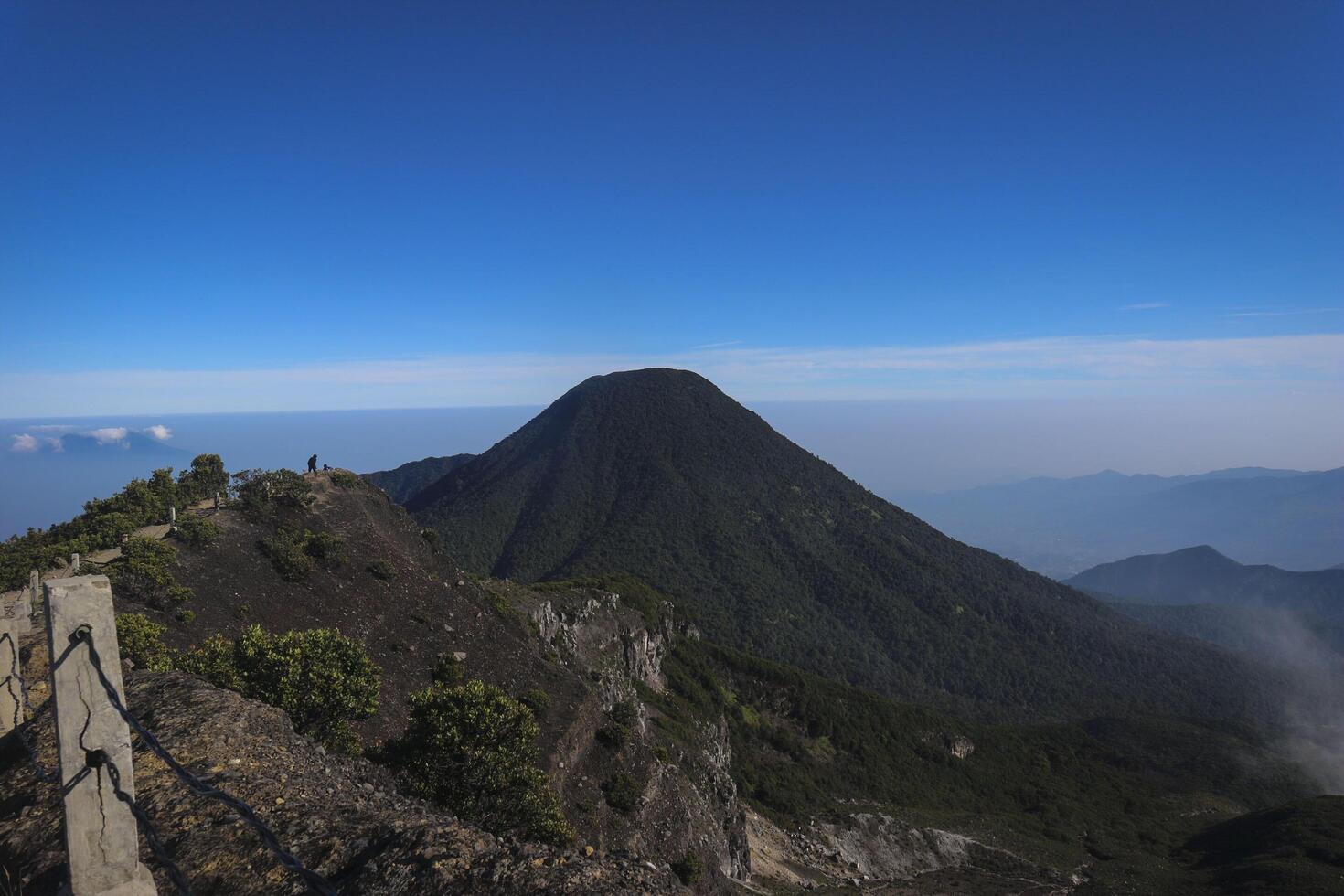 a person standing on a mountain top with a clear blue sky photo