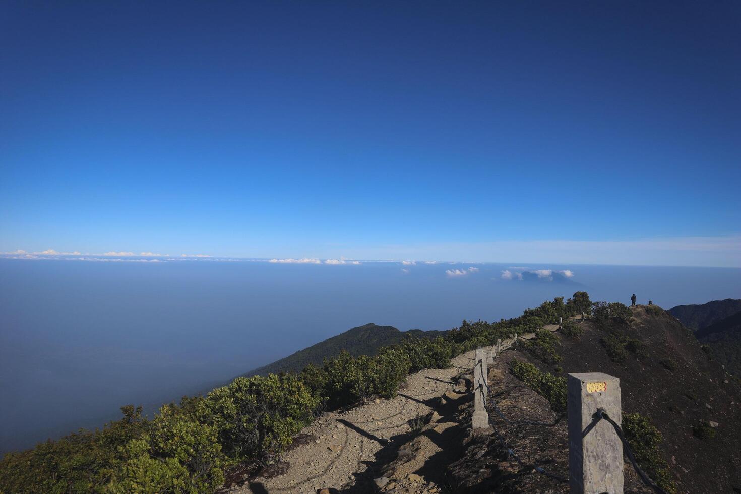 a person standing on a mountain top with a clear blue sky photo