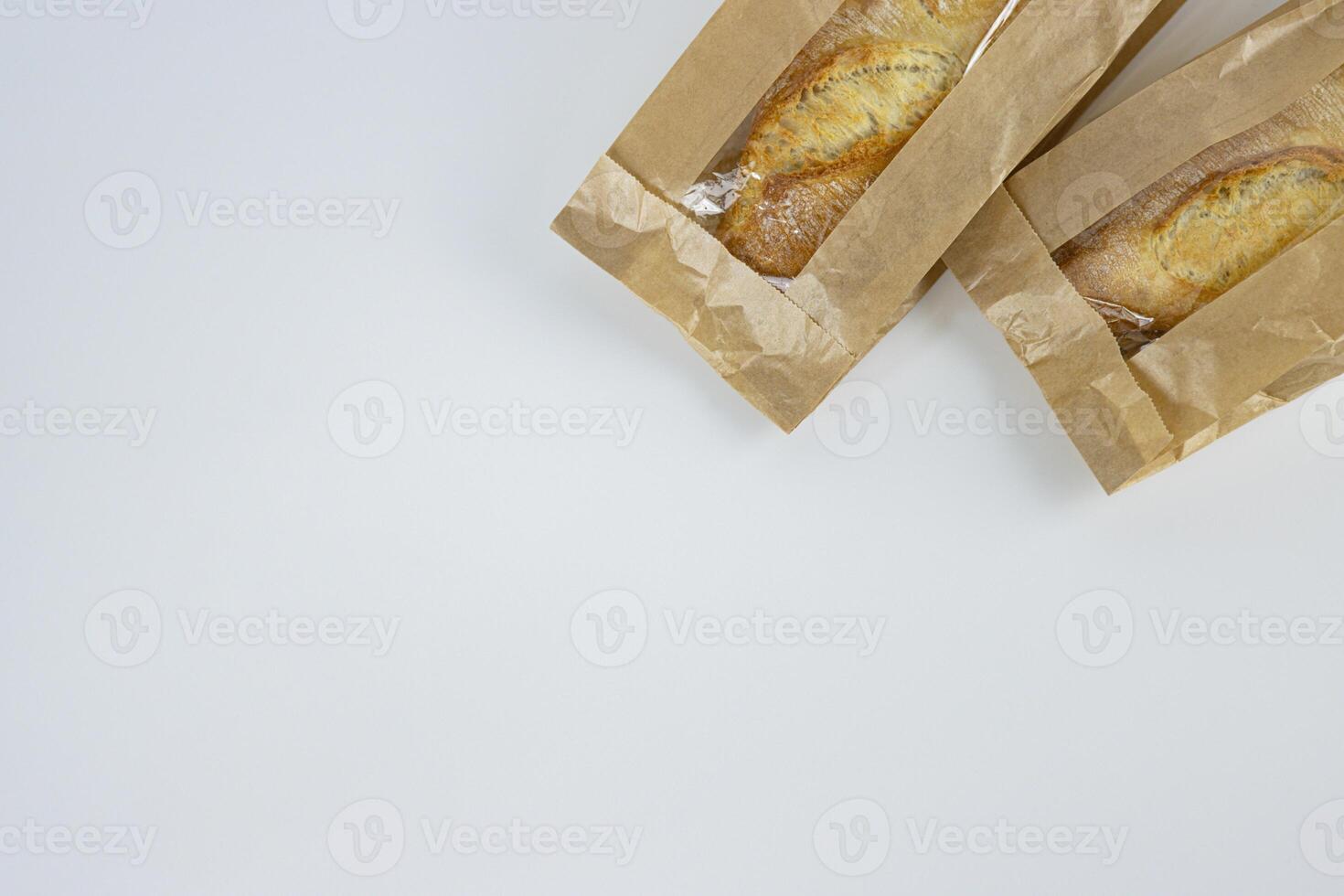Closeup of two french baguettes in the brown kraft paper plastic bag isolated on white background. Fresh baked bread for sell. High resolution studio photo. Minimalist design. Top view. Copy space. photo