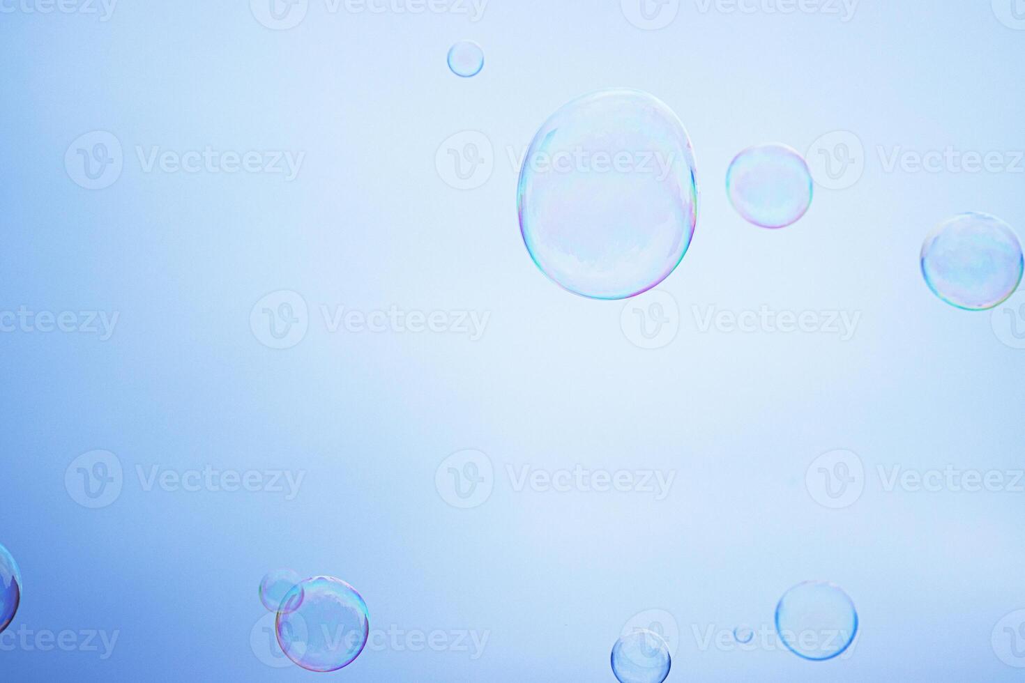 Large multicolored soap bubbles flying in the cloudy sky. Big bubble outdoors in the spring or summer street. Many bubbles isolated on white background. Simple creative concept. Close-up. Copy space photo