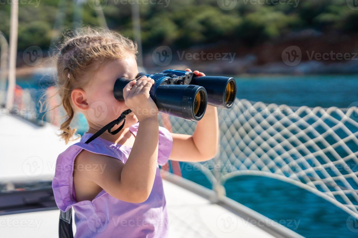 Little girl on a yacht looking through binoculars in the sea photo