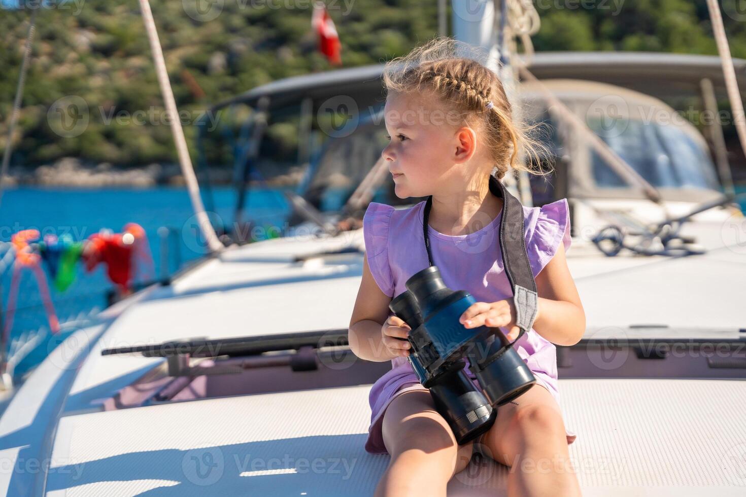 Little girl on a yacht looking through binoculars in the sea photo