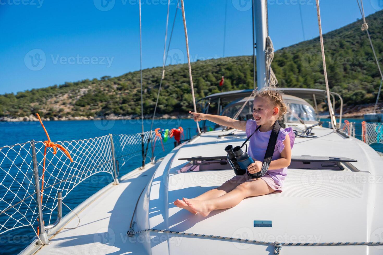 Little girl on a yacht looking through binoculars in the sea photo