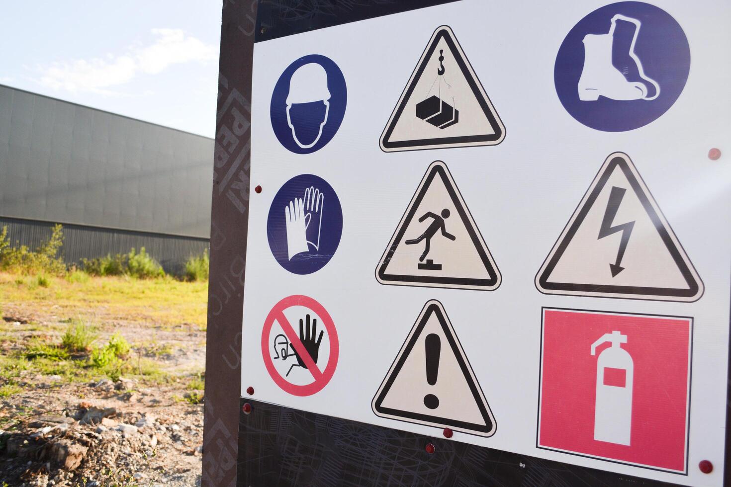 A board with warning signs about danger that stands before the start of construction on the field photo