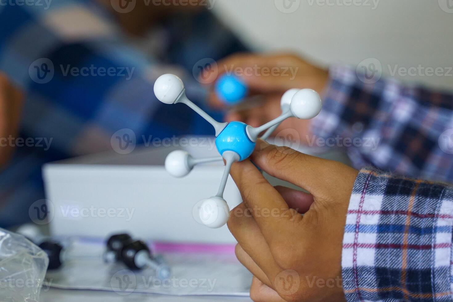 Hand holding a Simulate Shape of covalent molecules on a gray and white background. photo