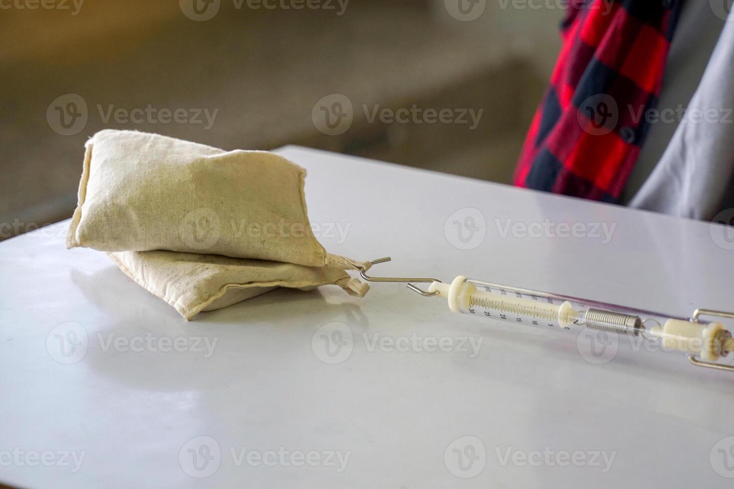 Asian students conduct experiments on friction Using a spring scale, pull 2 sandbags onto the table. Concept of science classroom, science skills, learning, science experiment and physics. photo