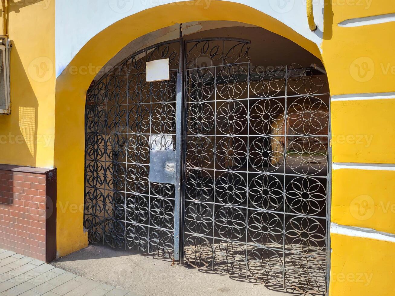 The facade of a yellow house with an arch and wrought iron gates. photo