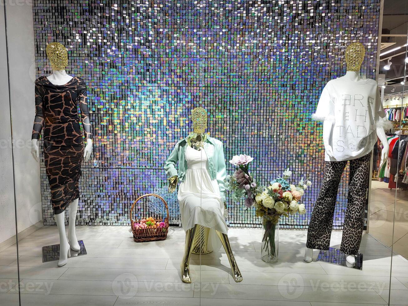 Three female mannequins in summer clothes in a shop window on a sparkling background photo
