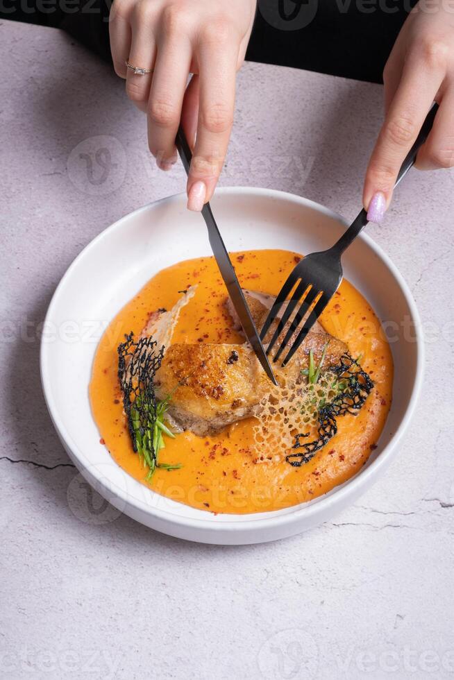 Plate with fried chicken and carrot and potato puree and female hands with cutlery photo