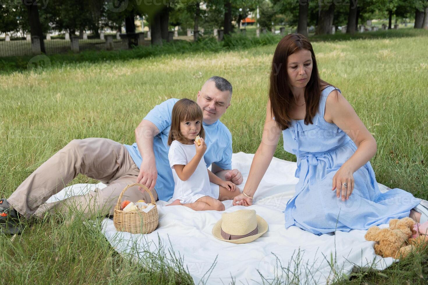 Mom, dad and daughter having fun on a picnic. Family vacation in nature photo