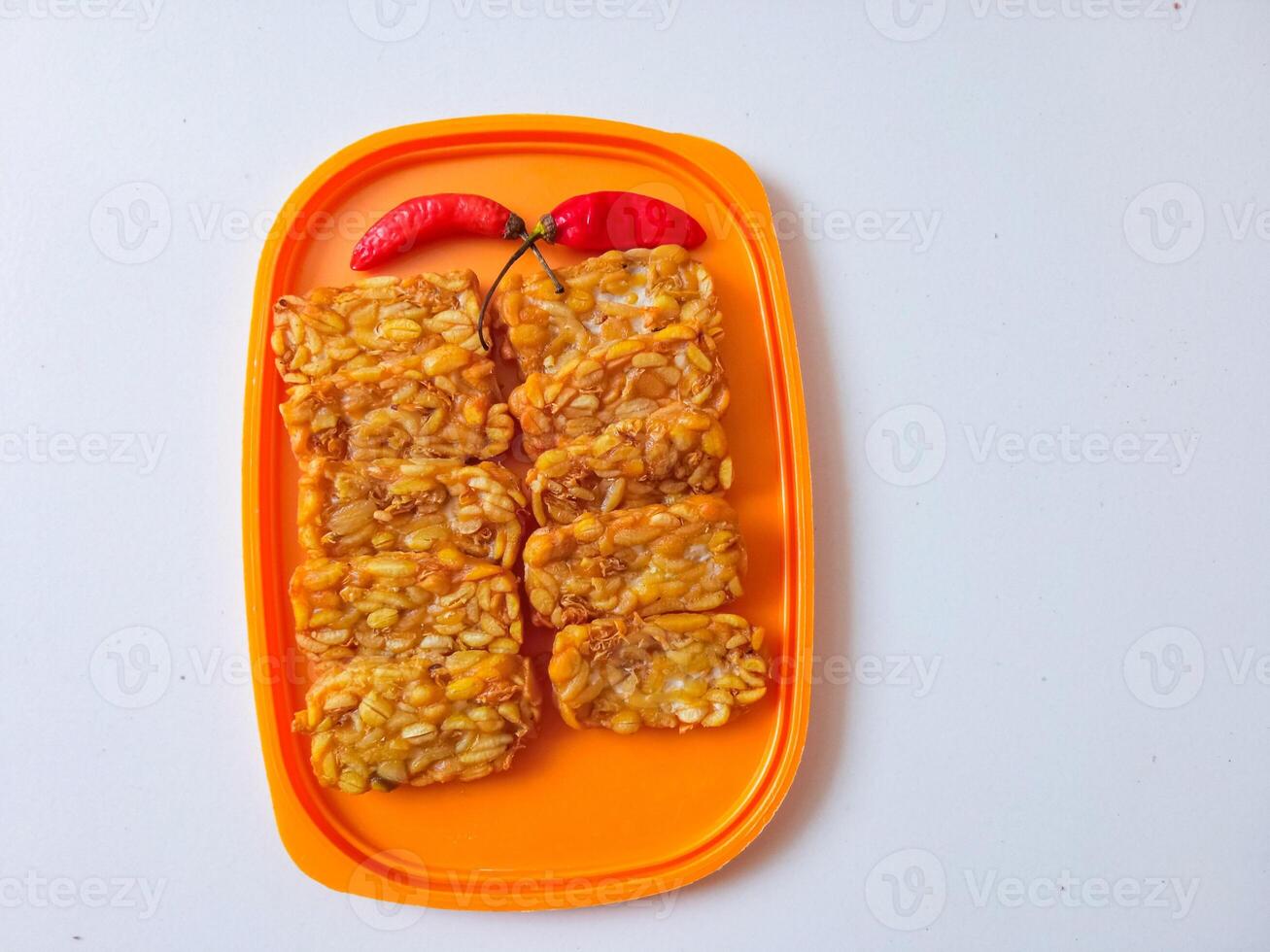 Fried tempeh is neatly lined up on a plate isolated on white photo