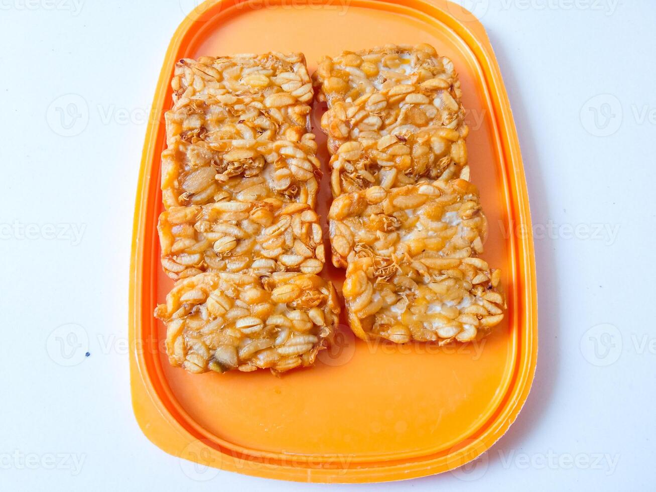 Fried tempeh is neatly lined up on a plate isolated on white photo