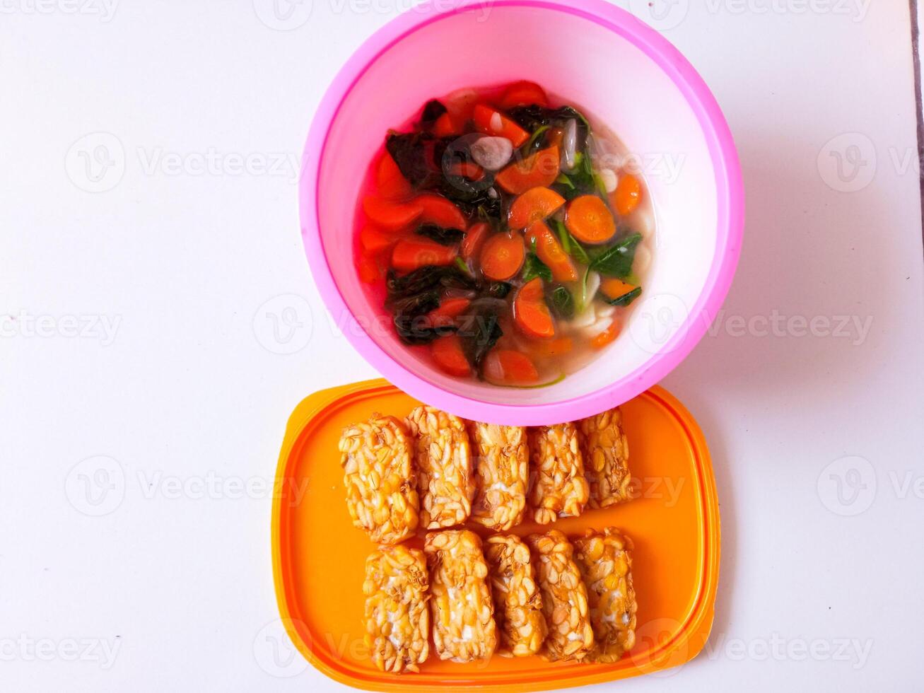 Fried tempeh and a bowl of spinach and carrots are ready to eat photo