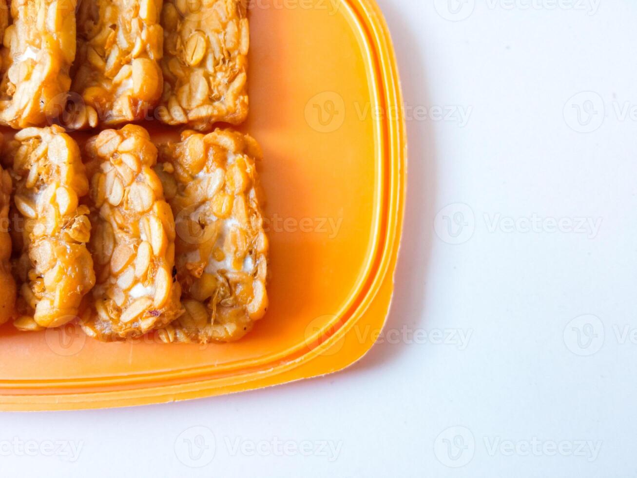Fried tempeh is neatly lined up on a plate isolated on white photo