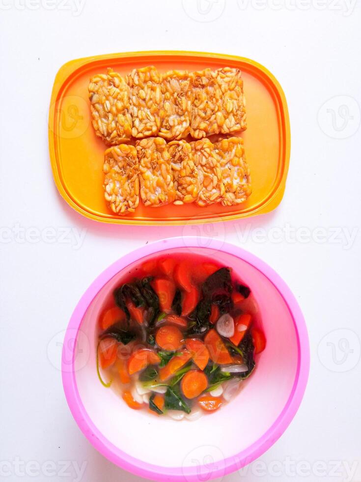 Fried tempeh and a bowl of spinach and carrots are ready to eat photo