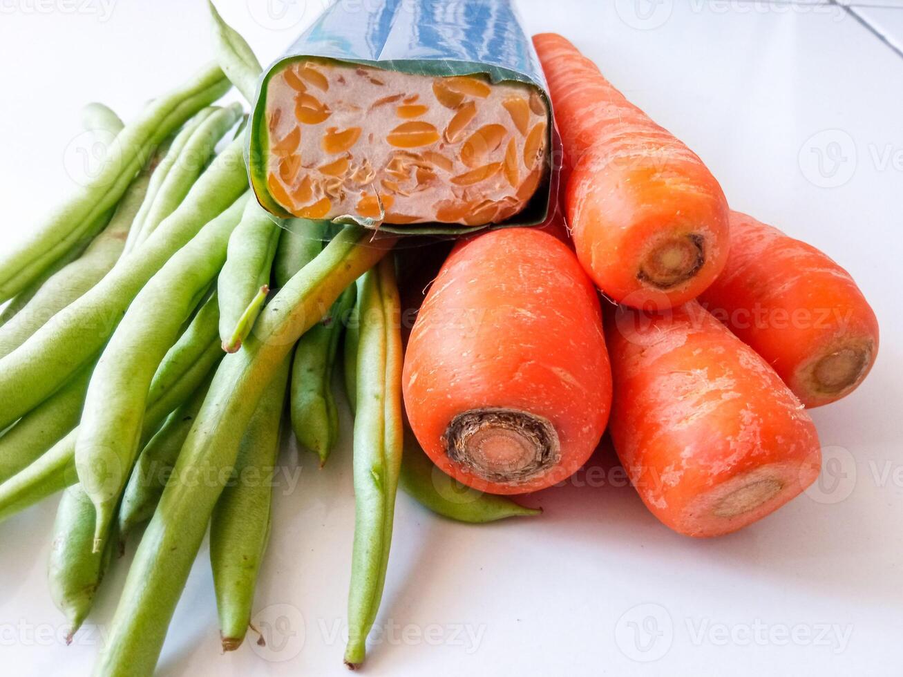 pile of green beans and carrots and tempeh isolate on white photo