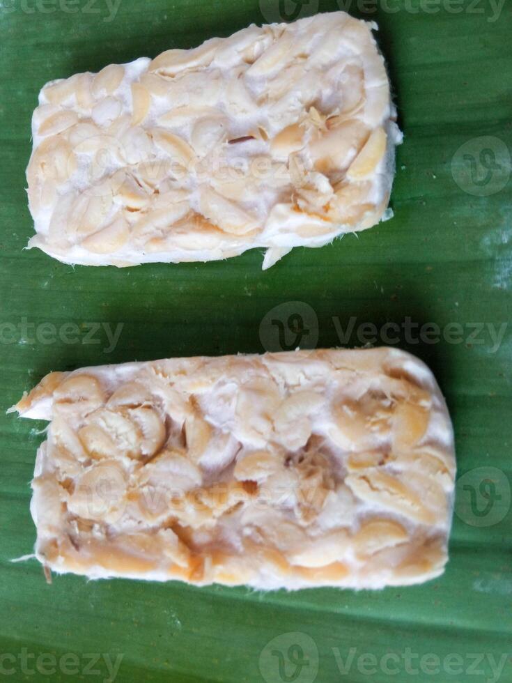 Tempeh slices on banana leaves before frying photo