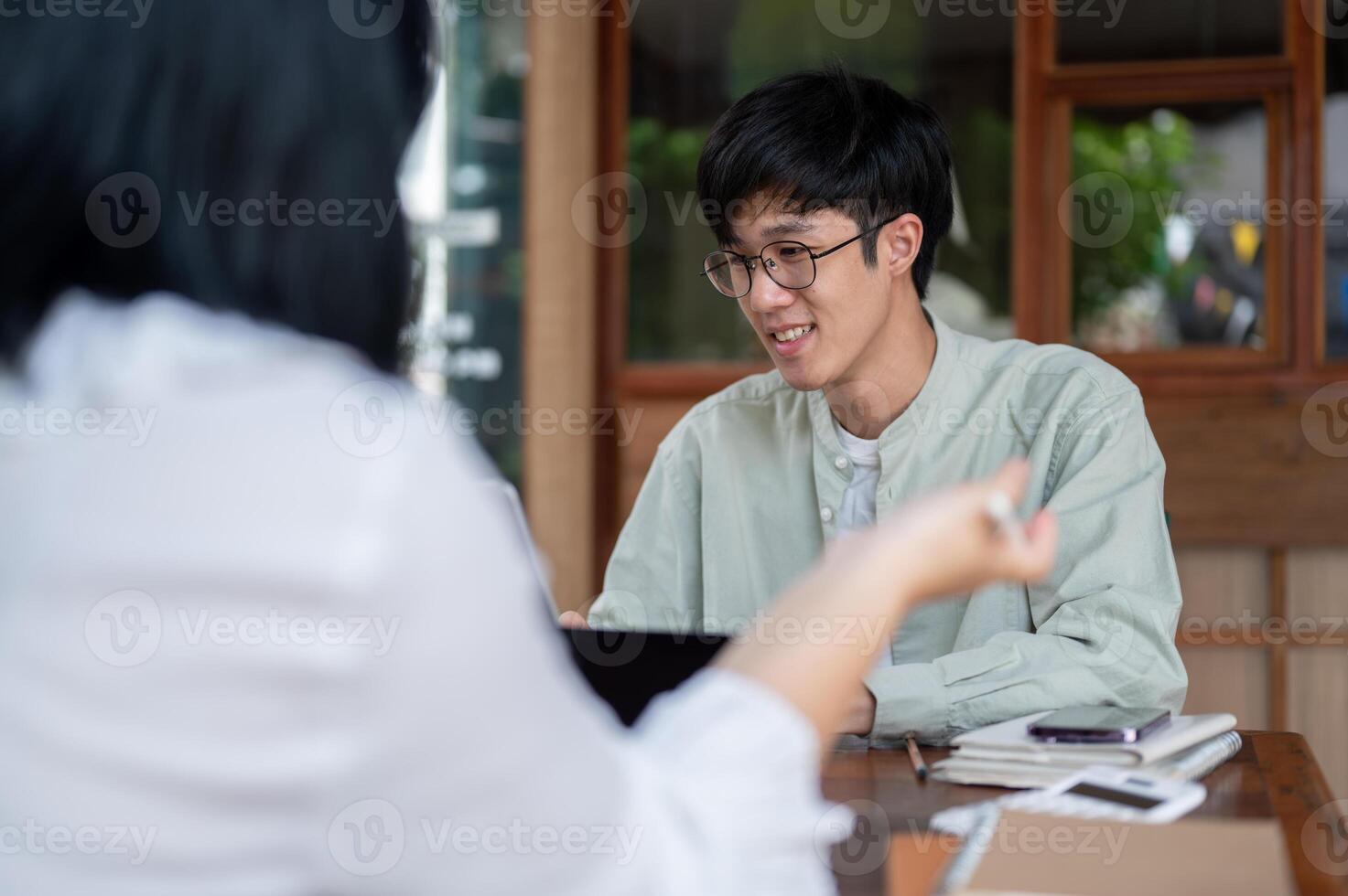 A young Asian man is having an informal meeting to discuss a project with his colleague at a cafe. photo