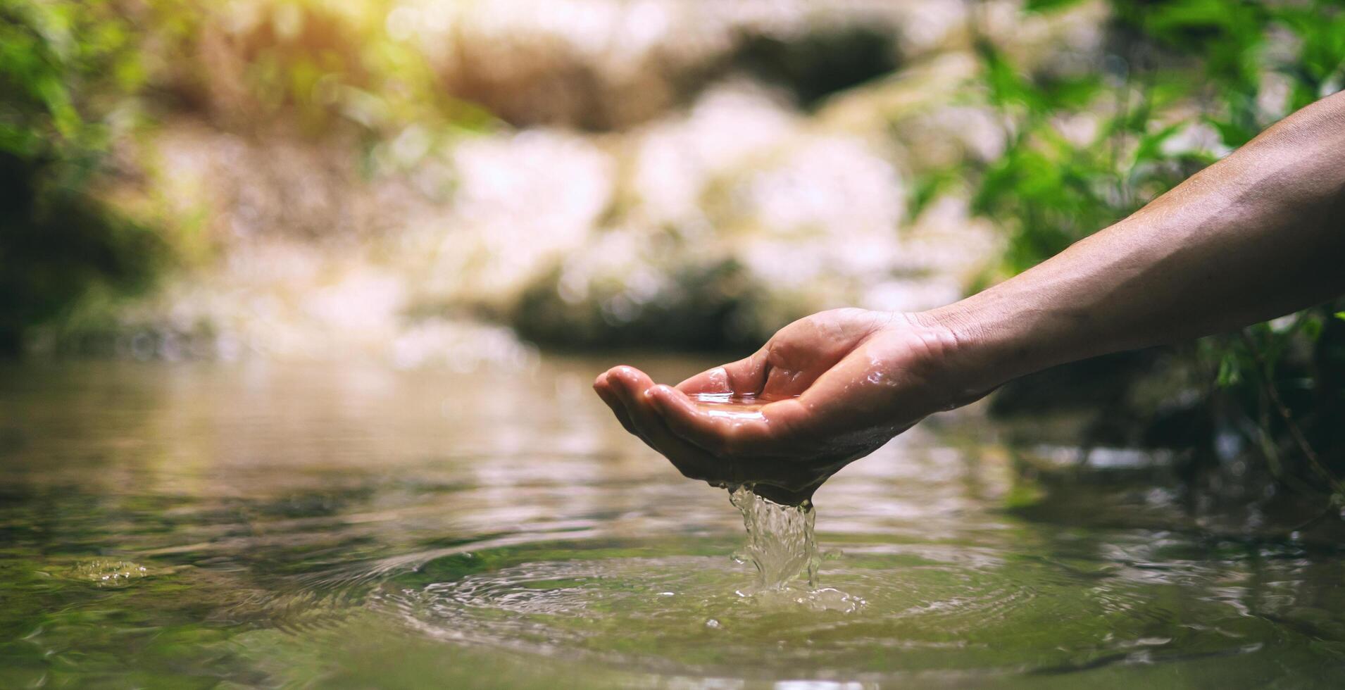 hand is in a stream of water, and the water is clear photo