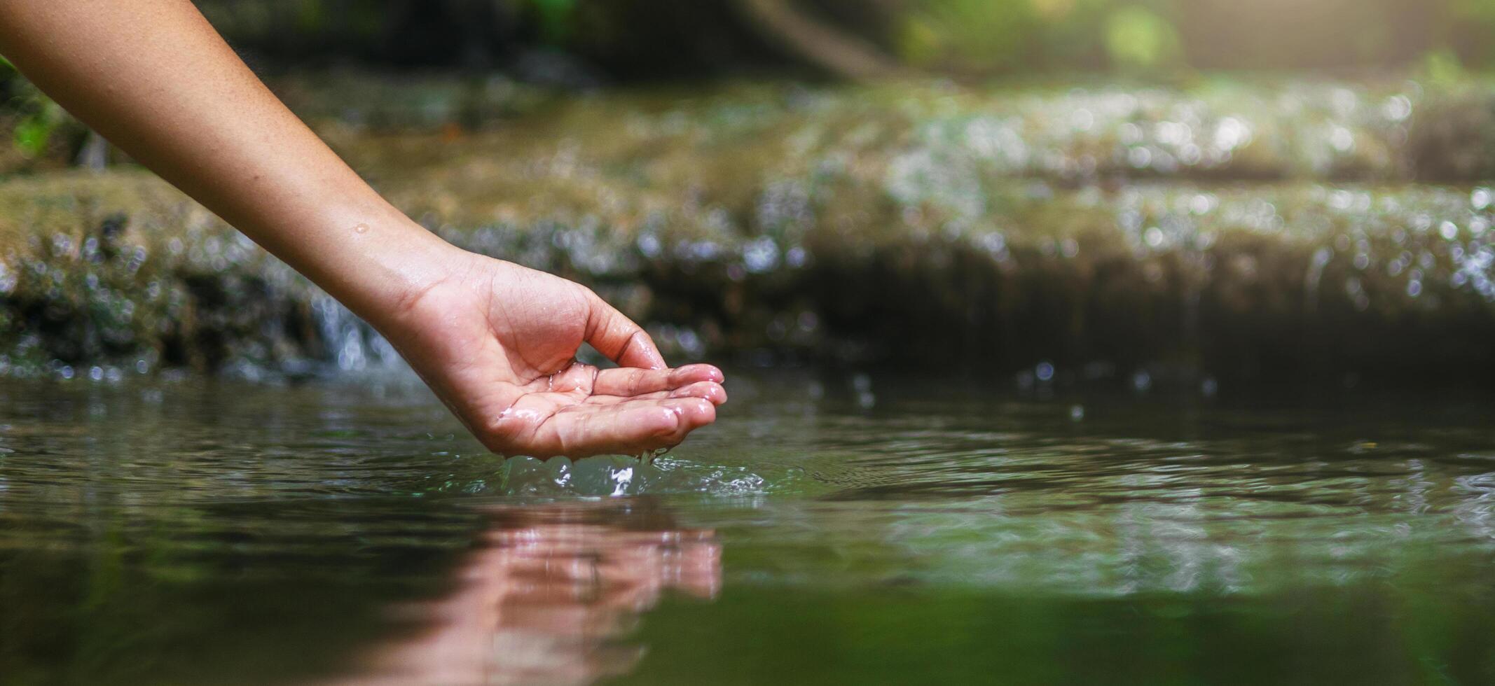 hand is dipping into a body of water, creating ripples in the water photo