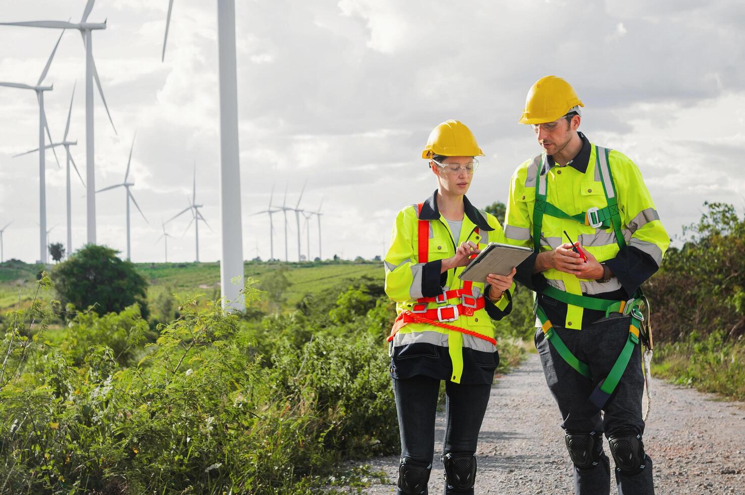 Two workers in safety gear are looking at a clipboard photo