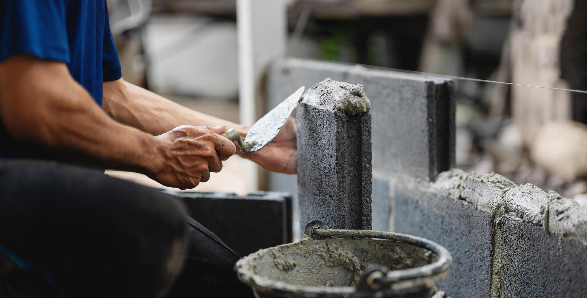 man is laying on the ground and using a trowel to spread cement photo