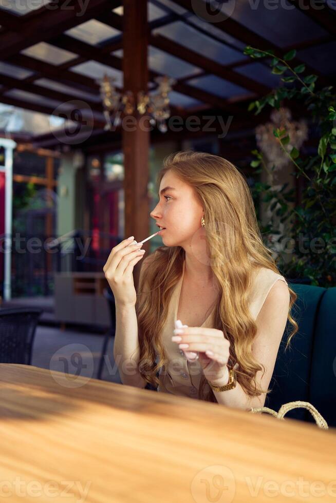a beautiful teenage girl in a peach fuzz suit with a vest, in the old money style in a fancy restaurant photo