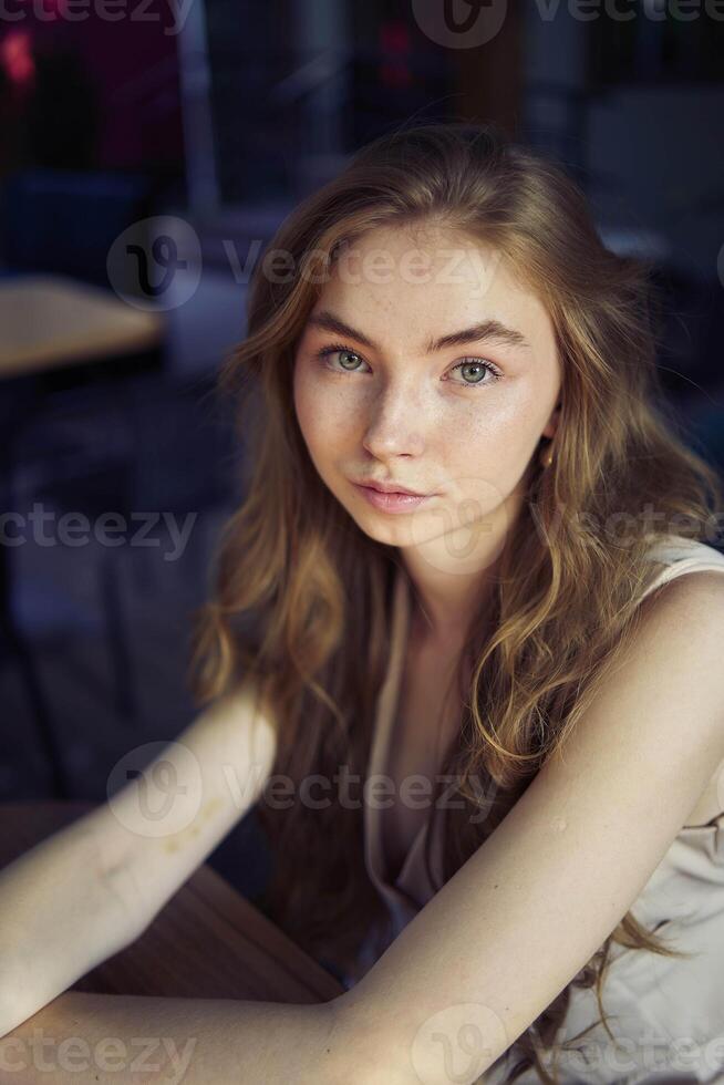 a beautiful teenage girl in a peach fuzz suit with a vest, in the old money style in a fancy restaurant photo