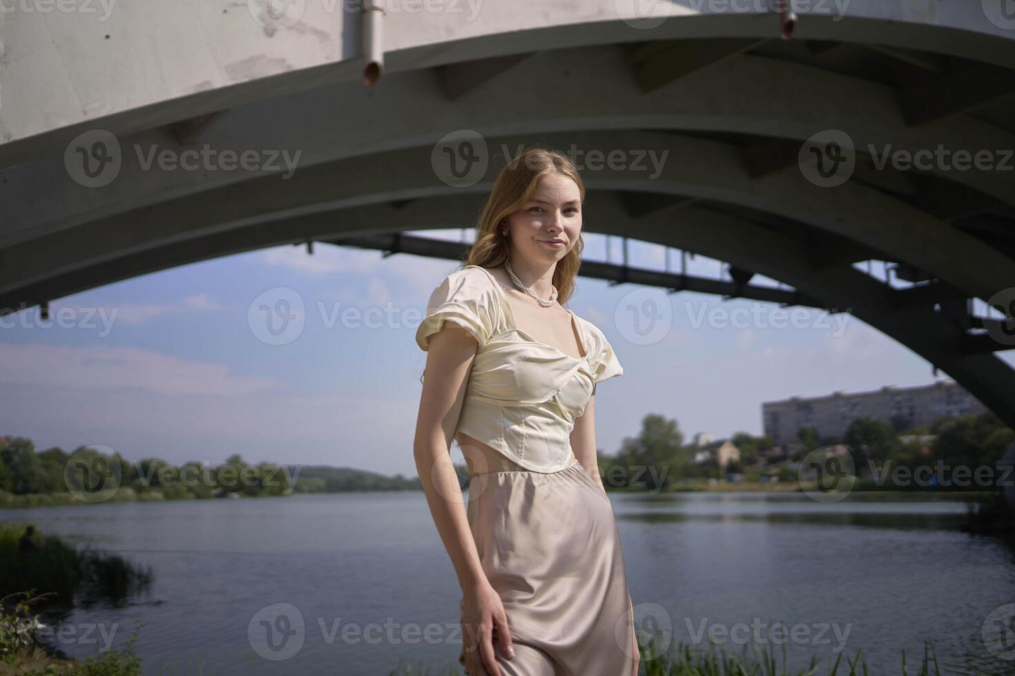 beautiful teenage girl in a silk skirt and corset in the old money style. Fashion photoshoot under the bridge. photo