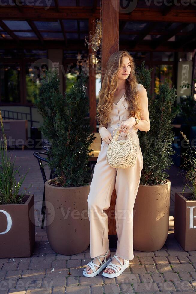 a beautiful teenage girl in a peach fuzz suit with a vest, in the old money style in a fancy restaurant photo