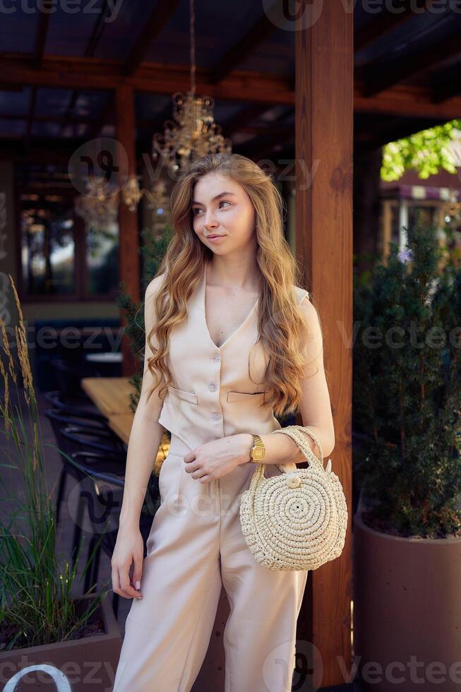 a beautiful teenage girl in a peach fuzz suit with a vest, in the old money style in a fancy restaurant photo