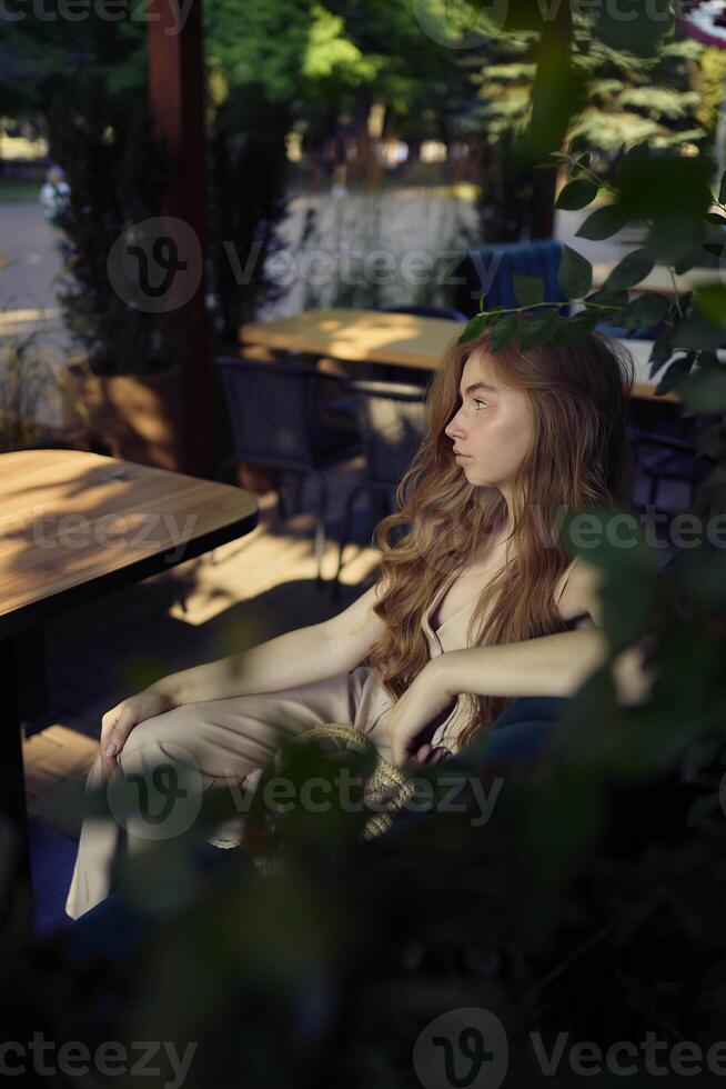 a beautiful teenage girl in a peach fuzz suit with a vest, in the old money style in a fancy restaurant photo
