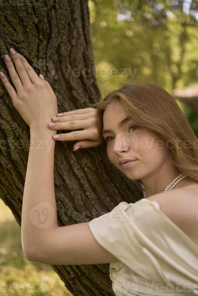 beautiful teenage girl in a silk skirt and a corset in the old money style walks in the park and along the river bank photo
