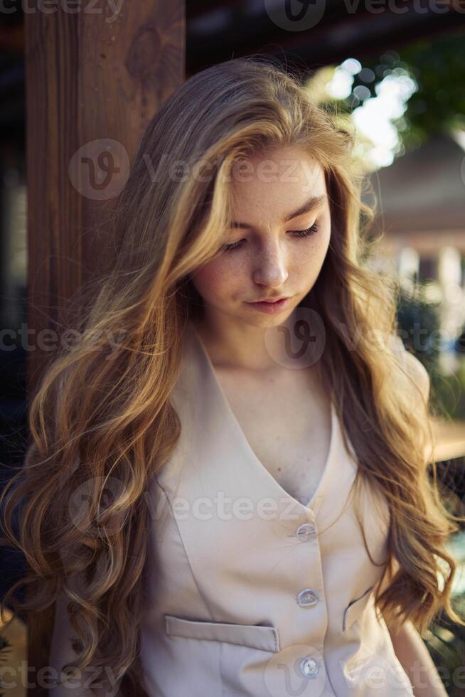 a beautiful teenage girl in a peach fuzz suit with a vest, in the old money style in a fancy restaurant photo