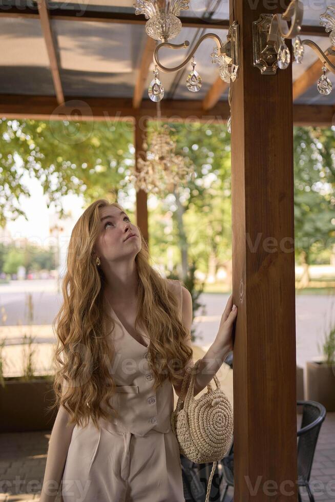 a beautiful teenage girl in a peach fuzz suit with a vest, in the old money style in a fancy restaurant photo