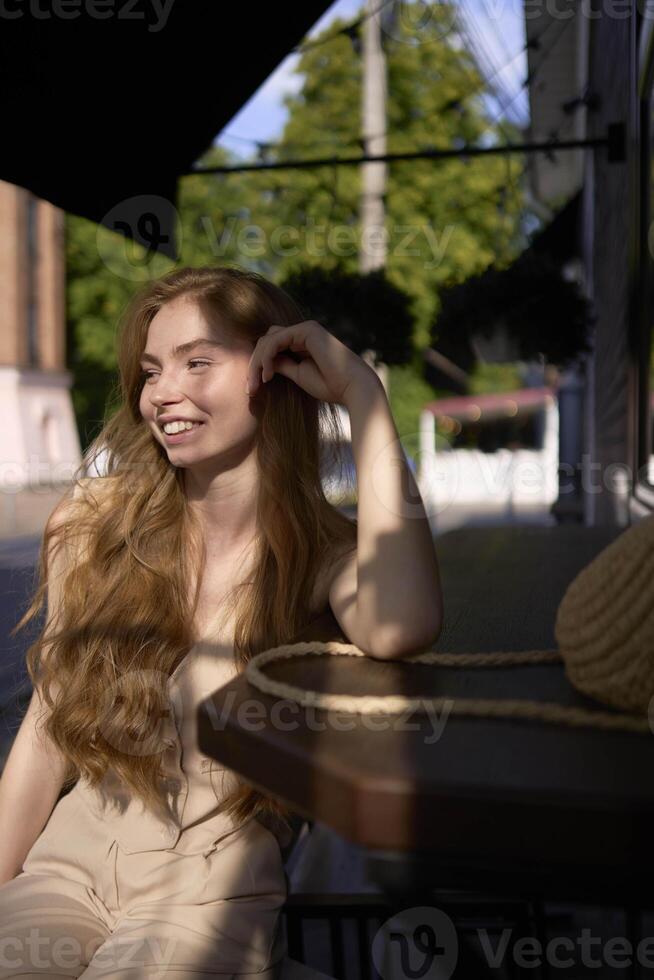 a beautiful teenage girl in a peach fuzz suit with a waistcoat in the old money style sits at the bar outside photo