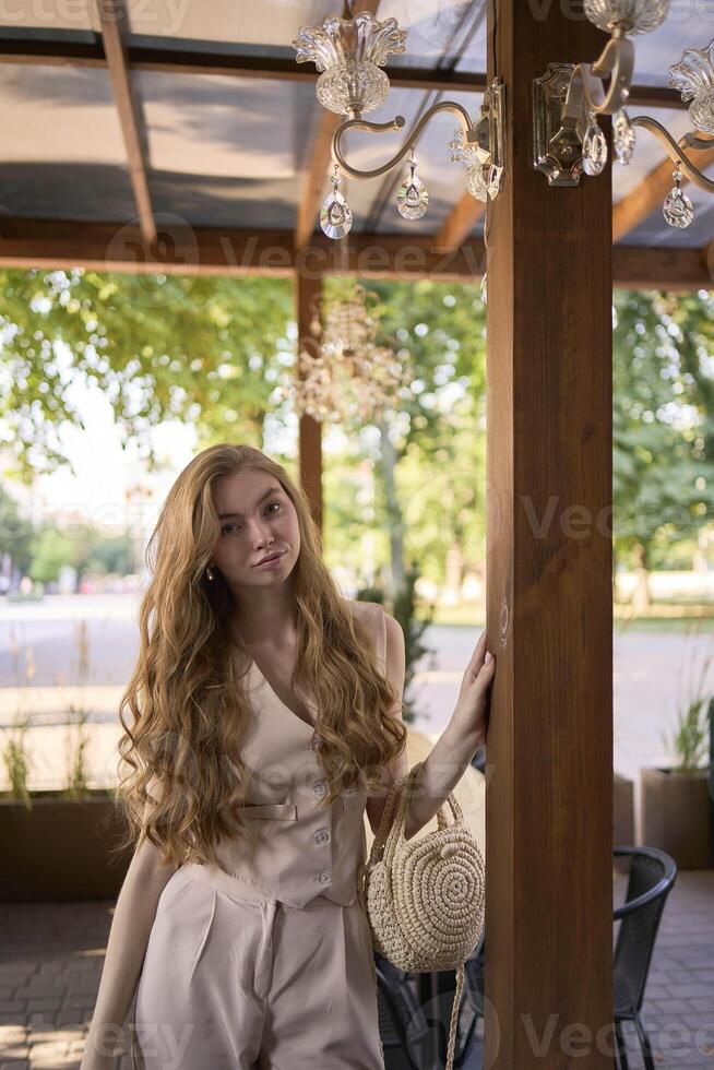 a beautiful teenage girl in a peach fuzz suit with a vest, in the old money style in a fancy restaurant photo