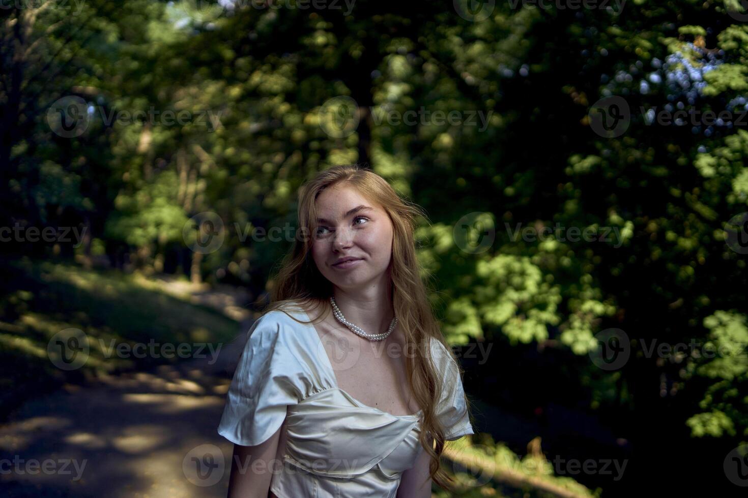 beautiful teenage girl in a silk skirt and a corset in the old money style walks in the park and along the river bank photo