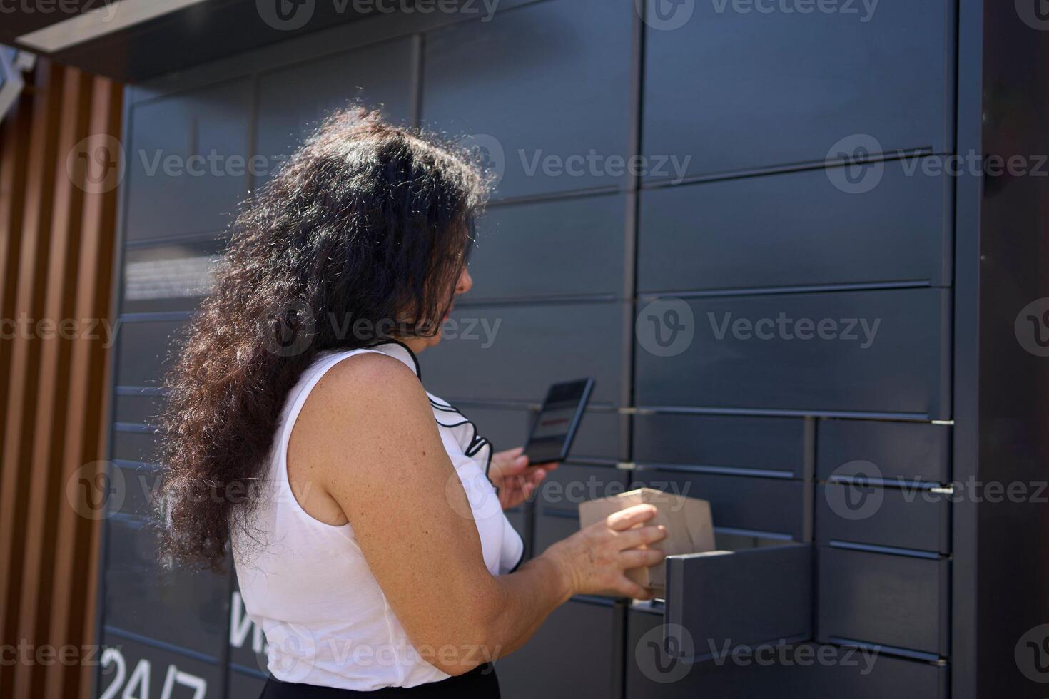 a woman picks up a parcel from a post terminal using a mobile application photo